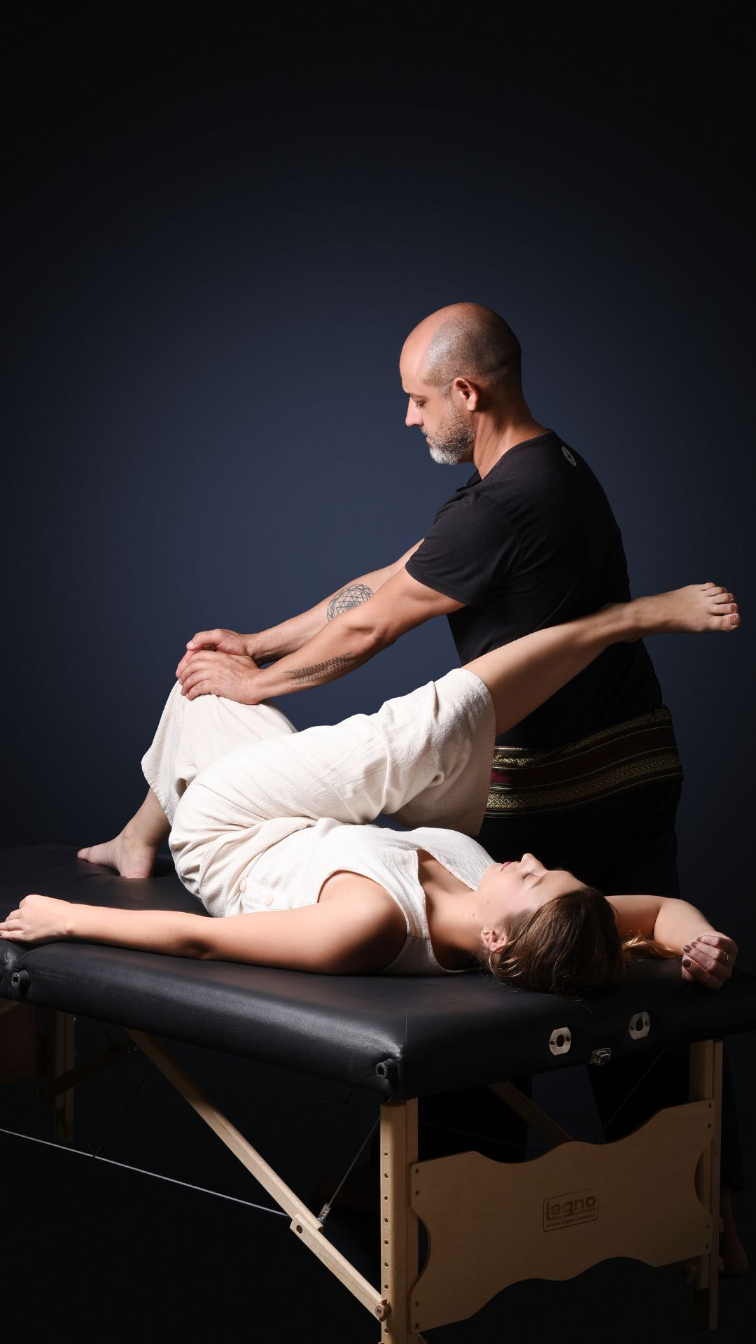 Sessão profissional de Thai Yoga Massage tradicional tailandesa realizada sobre o tatame